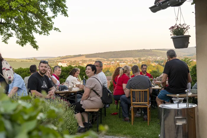 Hosté u degustačního stolu s výhledem na vesnici